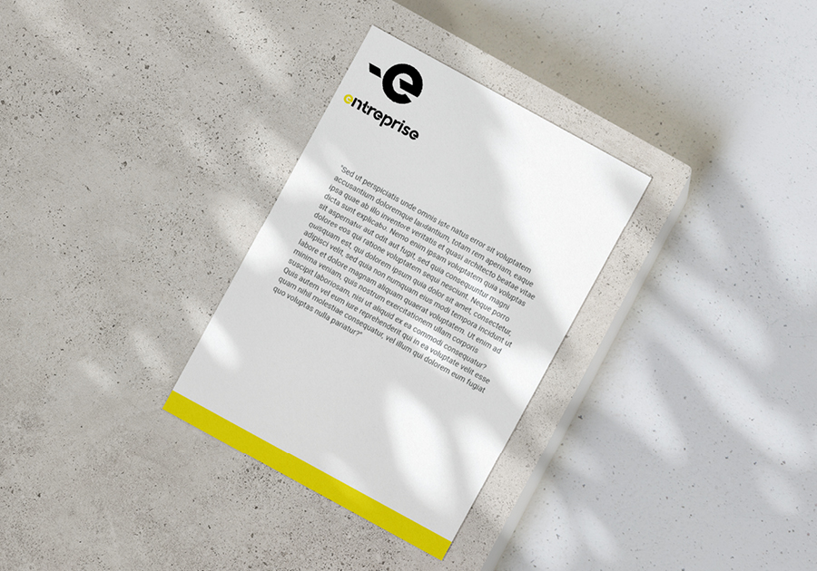 papel de carta blanco con el logotipo de la empresa y una franja amarilla sobre fondo de hormigón